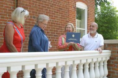 Nebraska State Regent, Judy Ekeler, and Lewis-Clark Chapter Regent, Mabel Petet, present a certificate to Patty Manhart, former May Museum Director and Jeff Kappeler, new museum director, celebrating the DAR grant given to the Dodge County Historical Society to rebuild the May Museum's porch, on which they are standing. Patty Manhart said, "Receiving these funds meant so much coming from DAR, a wonderful national historical organization."