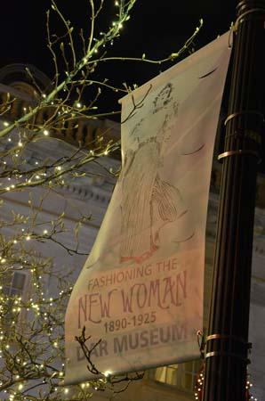 A banner for the DAR Museum exhibition, "Fashioning the New Woman: 1890-1925," illuminated by Christmas lights.