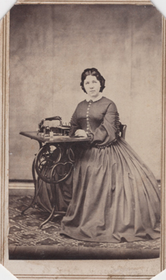 woman sitting at an 18th century sewing machine