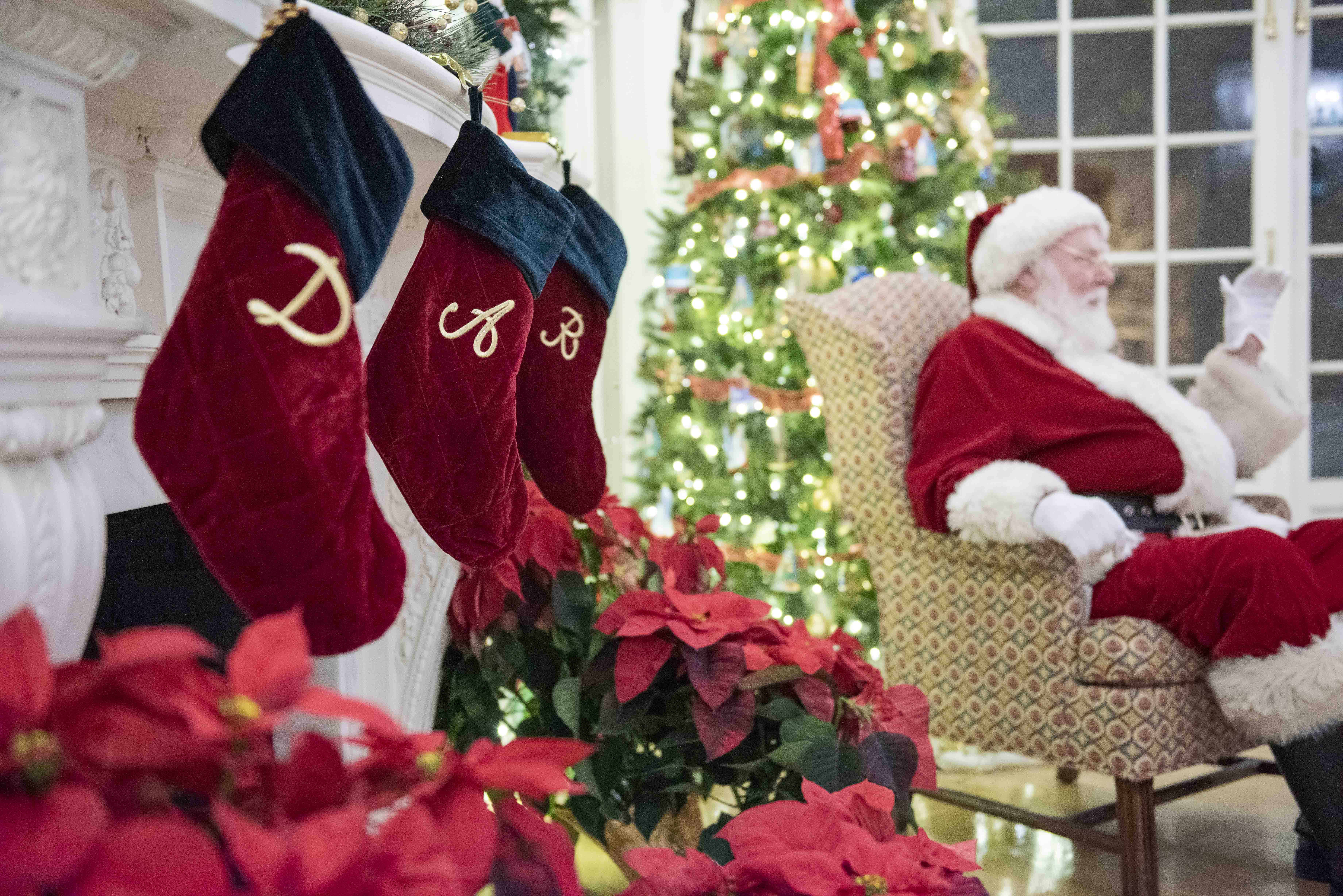 Santa sitting in chair by a tree and stockings that say D A R 
