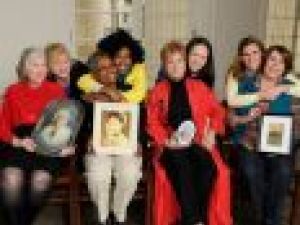 women sitting with photos of their ancestors while their child hugs them