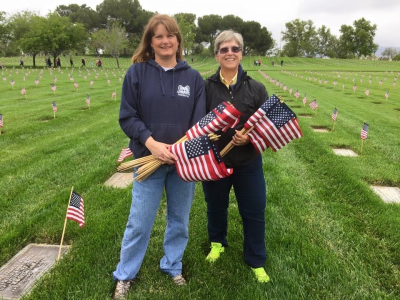 Ladies putting down american flags at graves