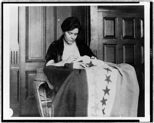 Alice Paul sewing a suffrage banner, c. 1912–1920 (Library of Congress).