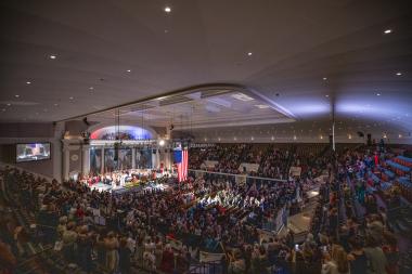 DAR Constitution Hall filled with DAR members and a flag hanging down on them. 