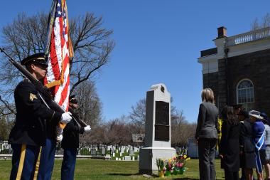 The Color Guard and representatives stand at attention as honors are rendered and TAPS is played.