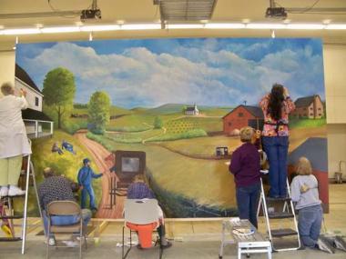 Alana Speckman, Eleanor Boston, and Jackie Gillespie, members of the Battle Creek Chapter, Michigan, have been involved with the painting, development and completion of three murals in the Convis Township Hall in Calhoun County, Michigan. Each mural is 9½ by 16½ feet and tells the history of the township. The first begins with the early settlers to the region in the early 1800s. It reflects the friendships and interactions of the settlers with Native Americans. The second mural is the period 1860 to 1920 an