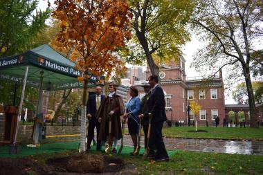 Special guests at the ceremonial tree planting stand in the shadow of historic Independence Hall with the newest addition to the park.