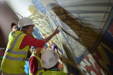 Conservators were brought in to develop a cleaning and stabilization strategy for the flag mural and states as well as to identify areas that might have been damaged and need minor-to-more-involved repairs. Here President Dillon is being shown places where the canvas stopped and portions were painted on the wall to fill in the gaps.
