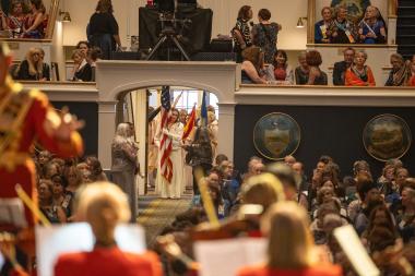 A woman in white carries the American Flag into DAR Constitution Hall. 