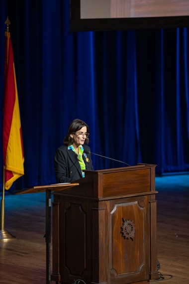 Pilar Llado, speaking at a podium. 