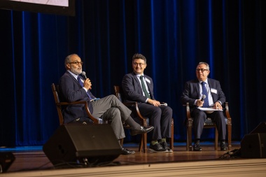 Three men speak on a panel. 