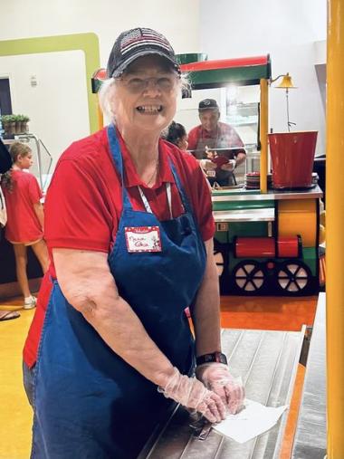 A member smiles while serving food. 