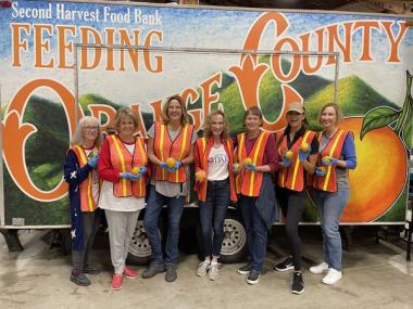 A group of members smile in front of a food bank truck. 
