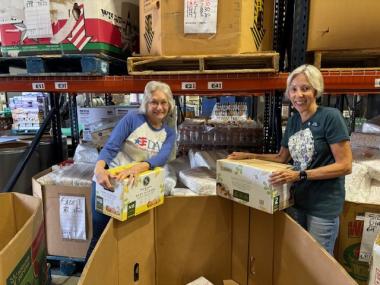 Two members smile while organzing donations. 