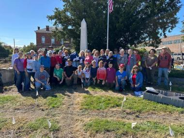 A group of members smiling in front of a memorial in a cemetery. 