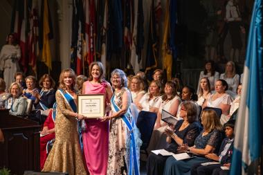 Woman accepting award with execs by her