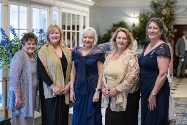 Women stand in entry hall around flowers 