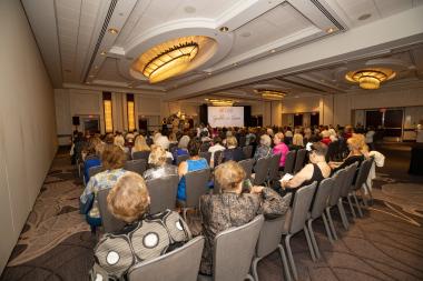 Women sit in conference room listening to presentation
