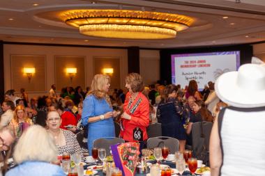Women sit and stand at luncheon talking