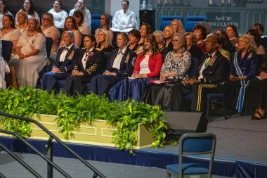 Military men and women sit on stage