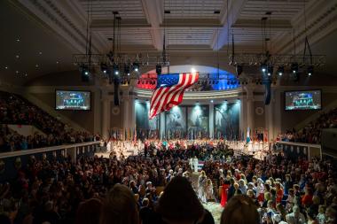 President of DAR processes in with the American flag flowing above her