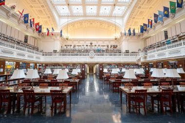 Interior of a large library with tables and chairs.