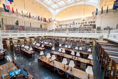 Library lined with rows of books, tables, and flags. 