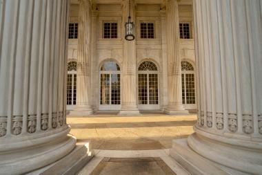 Columns and pillars of a building with windows, showcasing architectural elegance and symmetry.