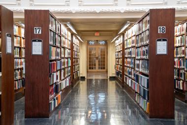 A long hallway with bookshelves and a large door.