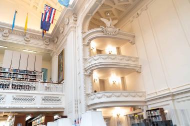 Library interior with expansive ceiling, bookcases, and comfortable seating areas.