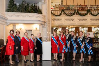 Executive officers stand in front of a Hanukkah menorah. 