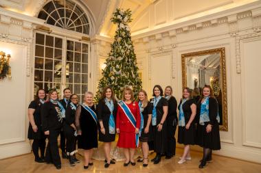 The President General and Vice President General pose in front of a Christmas tree with the pages. 