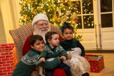 Three kids sit in Santa's lap. 