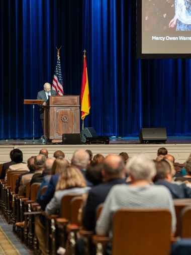 Man speaks from a podium onstage. 
