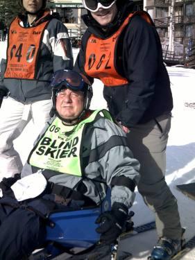 This skiier is ready to go - the volunteer will hold onto the chair to guide him down the hill.